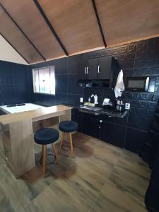 a kitchen with two stools and a counter in a room at Chalé Montanhez hidromassagem piscina in Caparaó Velho