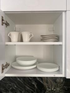 a white cabinet with plates and dishes in it at City Flat - Garage parking - TRITA SK in Poprad