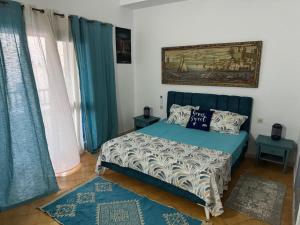 a bedroom with a blue bed and blue curtains at Velazzura Marina- Duplex à Monastir in Monastir