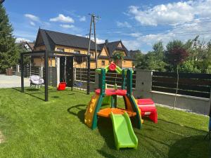 a playground with a slide in a yard with a house at DW Na Równi Białka Tatrzańska in Białka Tatrzanska