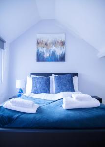a blue bed with two white pillows on it at Modern, Spacious Home Ideal for Work Teams and Groups in Luton