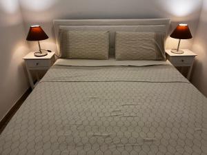 a bedroom with a white bed with two lamps at Casa sotto Mommio Castello in Piano di Mommio