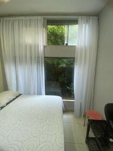a bedroom with a bed and a large window at Pousada Girassol in Rio de Janeiro