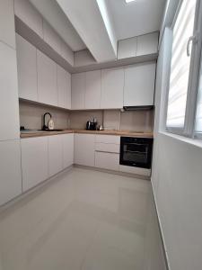 an empty kitchen with white cabinets and a window at Premium Central Skopje Apartments & Free Private Parking in Skopje