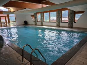 a large indoor swimming pool with blue water at Le Chardon Vert in Valmeinier