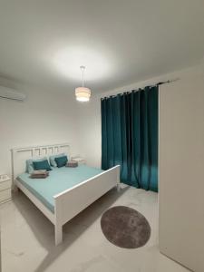 a bedroom with a bed with green curtains and a rug at FB Apartments in Ulcinj