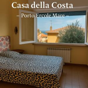 Dormitorio con cama de leopardo frente a una ventana en Casa della Costa - Porto Ercole Mare-, en Porto Ercole