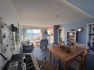 a living room with a table and a piano at Vue mer exceptionnelle-Appartement cosy à Erquy in Erquy