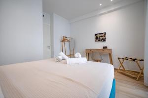 a white bedroom with a large bed with towels on it at Art 80 - A2 in Artemida