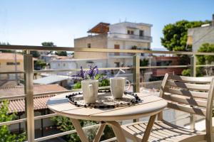 a table with two cups and flowers on a balcony at Art 80 - A2 in Artemida
