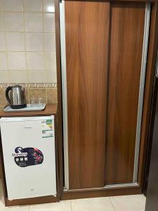 a refrigerator in a kitchen next to a wooden cabinet at فندق الأصالة البكية توصيل مجاني الى الحرم - ALAsalah ALBakkiya Hotel Free Shuttel Service in Al Masfalah