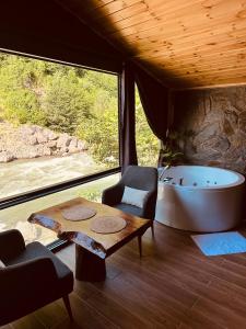 a room with a tub and a table and a chair at Ayder Luxury Villas & Bungalows in Çamlıhemşin