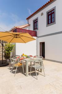 a patio with tables and umbrellas in front of a house at Just Like Home - Casa Cesário in Vila Praia de Âncora