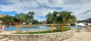 a pool at a resort with a fence and palm trees at Winterville Residence Gravatá por Yolo in Gravatá