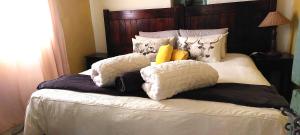 a bed with many pillows on top of it at The Anvil Rest Cottage in Calitzdorp