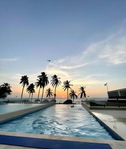 einen Pool mit Palmen und dem Meer im Hintergrund in der Unterkunft Wai Blue/Luxury Beachfront/ Bello Horizonte/ TTO03 in Playa Dormida