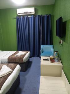 a room with two beds and a tv and blue curtains at Middle East Hotel Dubai in Dubai
