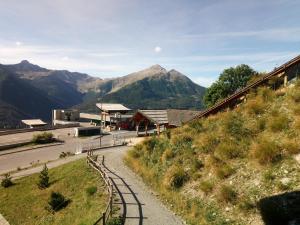 a path leading to a building with mountains in the background at Au bon endroit N1 - Appartement 2 pièces 5 à 7 personnes - proche pistes - coeur station - balcon in Orcières