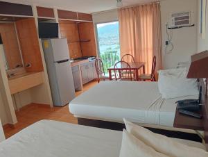 a room with two beds and a kitchen with a table at Alba Suites Acapulco in Acapulco