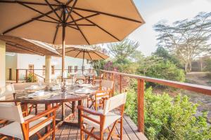 a wooden deck with a table and chairs and an umbrella at Wildebeest Eco Camp in Nairobi