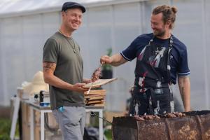 dos hombres están cocinando comida en una parrilla en Paratiisi Camping, en Jälist