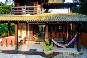 ein Haus mit einer Terrasse mit Tisch und Stühlen in der Unterkunft Casa Juréia com piscina aquecida, a 350m da praia - Litoral Norte in São Sebastião