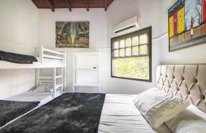 ein Schlafzimmer mit einem Bett und zwei Etagenbetten in der Unterkunft Casa Juréia com piscina aquecida, a 350m da praia - Litoral Norte in São Sebastião