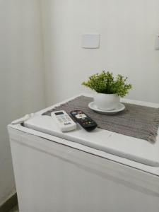 a table with two remote controls and a plant on it at Pousada La Floratta in Paulista