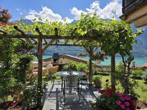 a patio with a table and chairs under a pergola at Chalet Swiss Alps in Niederried +26 photos