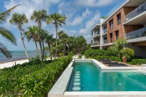 a swimming pool next to a building and the beach at 3BR Beachfront with Private Rooftop at Tankah Bay in Tulum