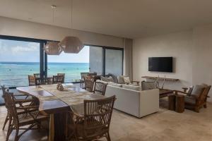 a living room with a table and a couch and the ocean at 3BR Beachfront with Private Rooftop at Tankah Bay in Tulum