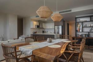 a living room with a wooden table and chairs at 3BR Beachfront with Private Rooftop at Tankah Bay in Tulum +18 photos