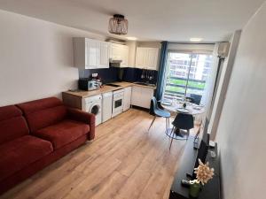 サン・シプリアン・プラージュにあるLe perroquetの赤いソファとキッチンのあるリビングルーム