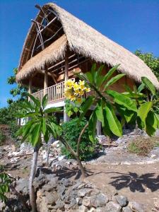 a house with a straw roof and two palm trees at The Somayan Bungalows in Nusa Penida