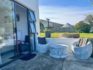 a patio with two chairs and a table and a window at Joy-South Studio in Agulhas