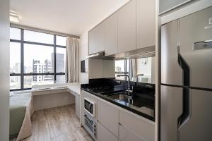 a kitchen with white cabinets and a large window at Apto com piscina aquecida e rooftop in Curitiba