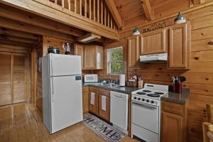 a kitchen with a white refrigerator and wooden cabinets at Escape to the Smokies- Pool, hot tub, cozy cabin, Pigeon Forge in Pigeon Forge