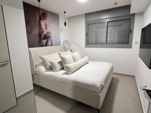 a room with a bed with white pillows and a window at Emmanuel suits in Eilat