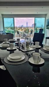 einen Tisch mit Tellern, Tassen und Stühlen in einem Zimmer in der Unterkunft Puebla Vista Malinche in Lomas de Angelopolis