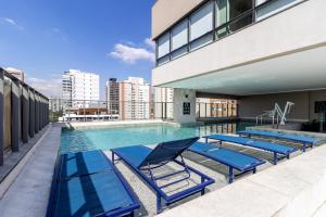 a swimming pool with blue lounge chairs on a building at BSR Luxe Studio next to Allianz Park w Rooftop Pool and Pet Friendly in São Paulo