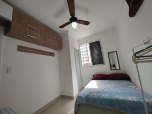 Un dormitorio con una cama y un ventilador de techo. en Apê da Pê, en Praia Grande