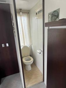 a small bathroom with a toilet with a window at Casa Cany in Barreiros