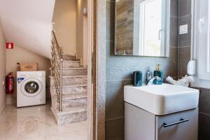 a bathroom with a sink and a washing machine at Eunoia Luxury Villas in Fanárion +77 photos