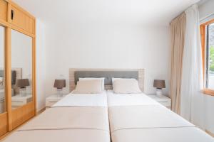a white bedroom with two beds and a window at Sunset view, Los Cristianos - Port Royale in Los Cristianos