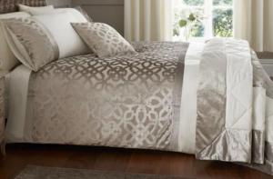 a bed with a gray and white comforter and a window at Galgorm Barn in Ballymena