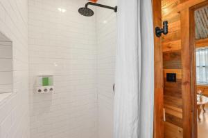 a white bathroom with a shower with a wooden door at RusTx Ranch Unit 7- Music in Wimberley +15 photos