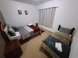 Un dormitorio con dos camas y una ventana. en Casa Planalto Gramado, en Gramado