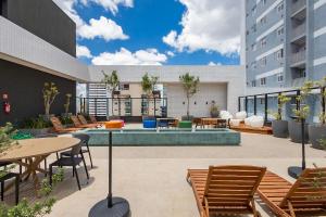 an outdoor patio with tables and chairs and a pool at Apto no All Batel finamente mobiliado perto do shopping Curitiba in Curitiba