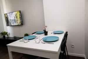 a white table with blue plates and glasses on it at Le 3 Chambres Parking Proche Tram in Clermont-Ferrand