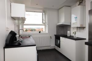 a kitchen with white cabinets and a black counter top at Le 3 Chambres Parking Proche Tram in Clermont-Ferrand +17 photos